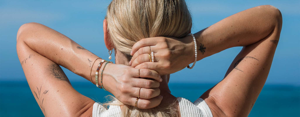 Model wears beaded, gemstone and gold chain bracelets. Shop bracelets online at Wanderlust Life Jewellery.