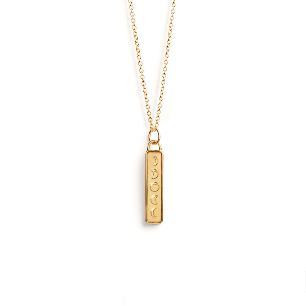 Wanderlust Life Aqua Pendant Necklace. New in the Elemental Collection,a vertical bar decorated with moon phases hands from a gold chain necklace. The reverse of the pendant is blank for complimentary engraving. Designed in our Devon studio, and handcrafted in the UK by our Wanderlust Life global artisan partners with 100% recycled silver.