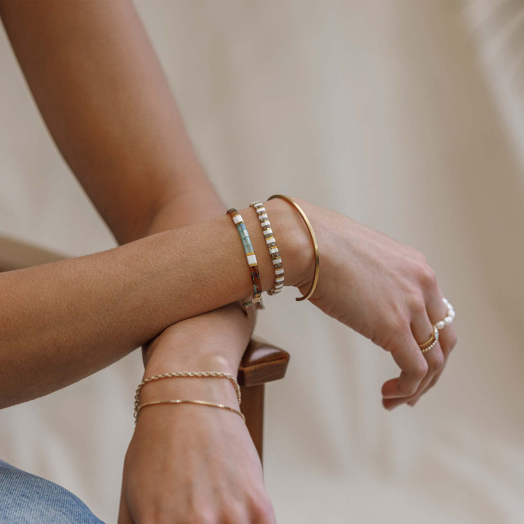 The Essaouira Layering Bracelet is a multicolour beaded bracelet with shades of sea foam green, white, gold and tortoise. Styled in a bracelet stack with the Terrazzo Slider bracelet and fine Nomad cuff.
