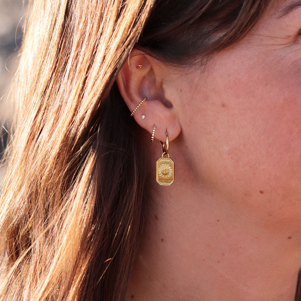 Solstice petite gold hoop earring. A series of miniature gold orbs form a tiny huggie hoop that delicately encloses the lobe. Proudly designed in Devon & handcrafted by our Wanderlust Life global artisan partners.