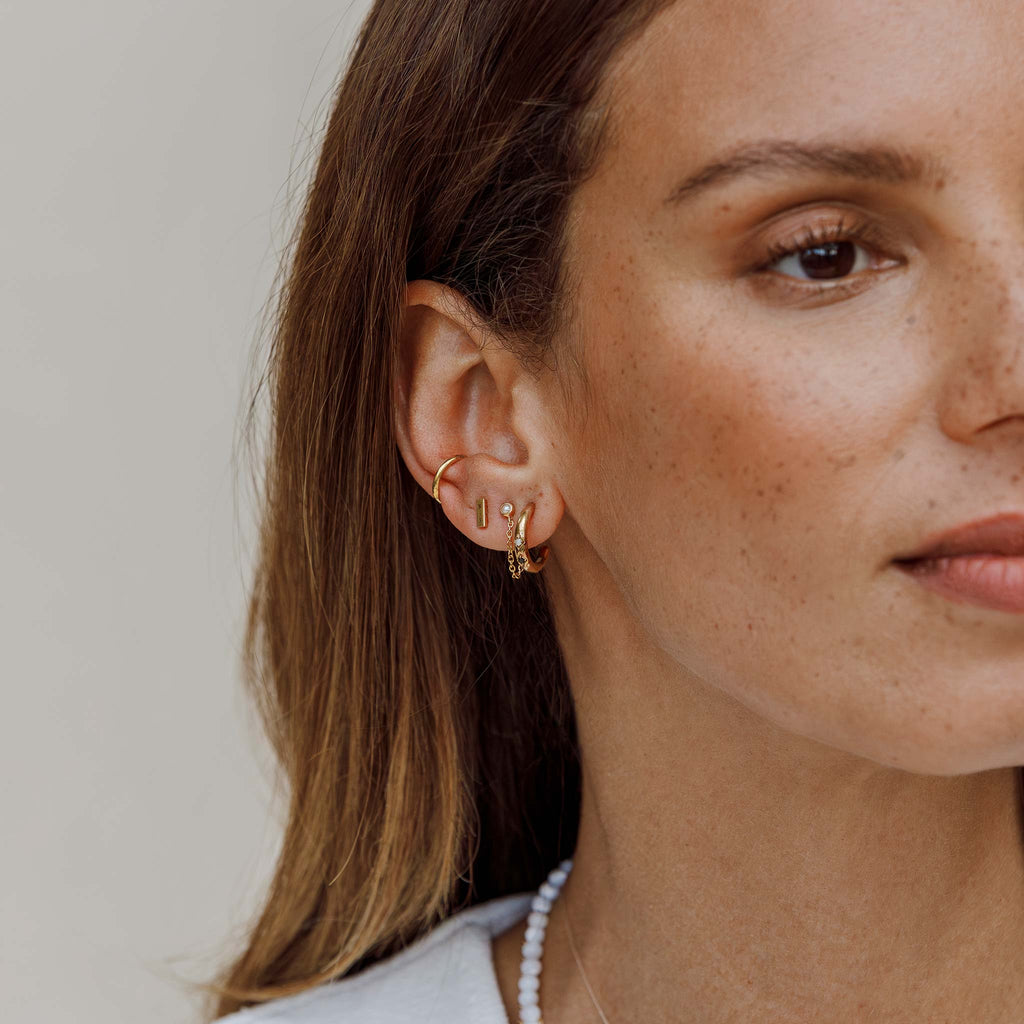 Hoop earrings with pearl and black spinel gemstones are styled in this ear stack with pearl chain studs and tonina bar stud earrings and a gold cuff. Creating an ear stack with edge. Gold vermeil jewellery designed in the UK and handcrafted by our Wanderlust Life Artisan Partners.