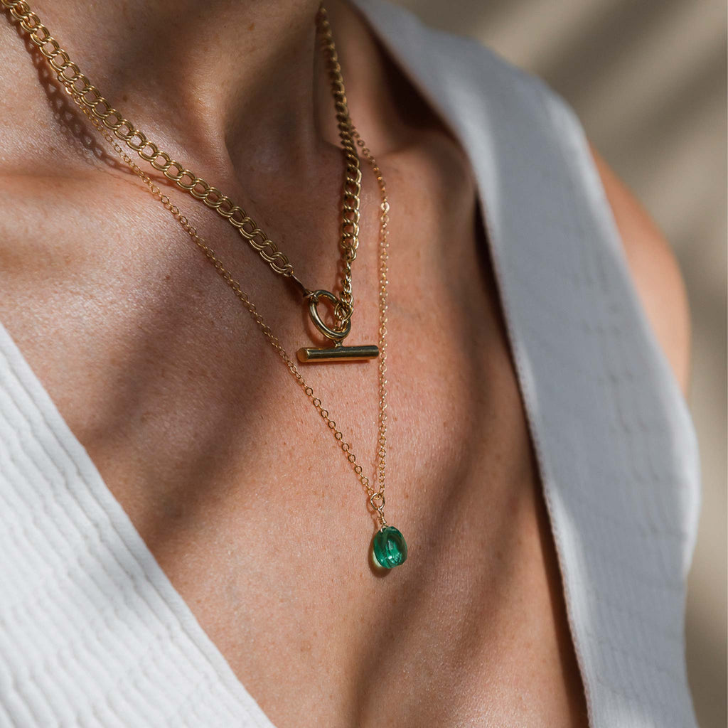 The Morgan Necklace is a statement double curb chain with a t-bar pendant. It's styled here in a necklace stack with a green quart gemstone necklace hanging below it.