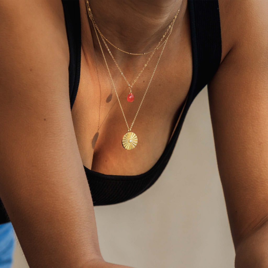 The Orange Carnelian gemstone pendant necklace is seen worn with the statement Pearl Sundial Necklace and Satellite Layering Chain at a choker length.