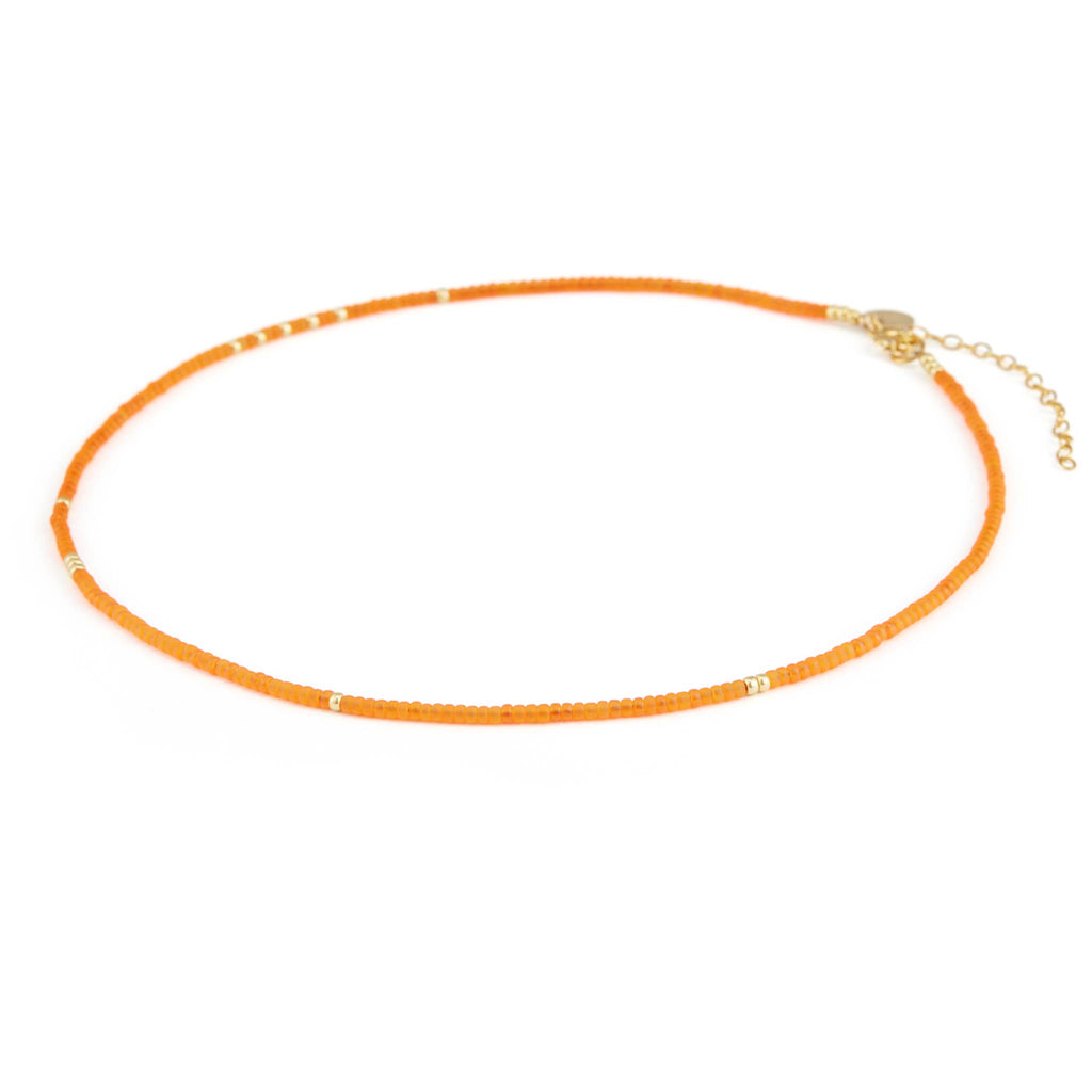 A beaded choker style necklace with sunset orange and gold beads in an irregular and minimal pattern.