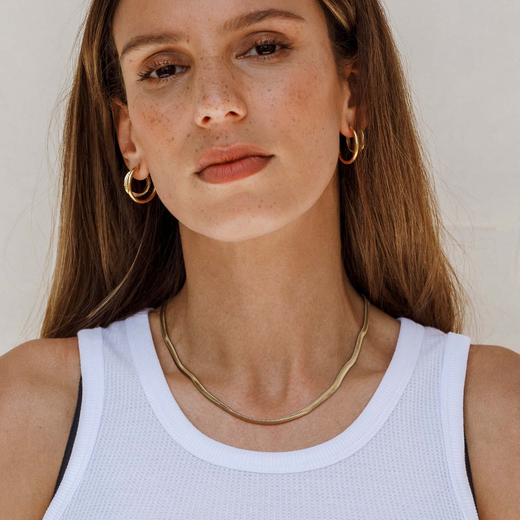 The Paseo Herringbone Chain Necklace is a signature statement necklace in an iconic and timeless wide snake chain style. Worn with go-to Silke and Plumo Hoops.