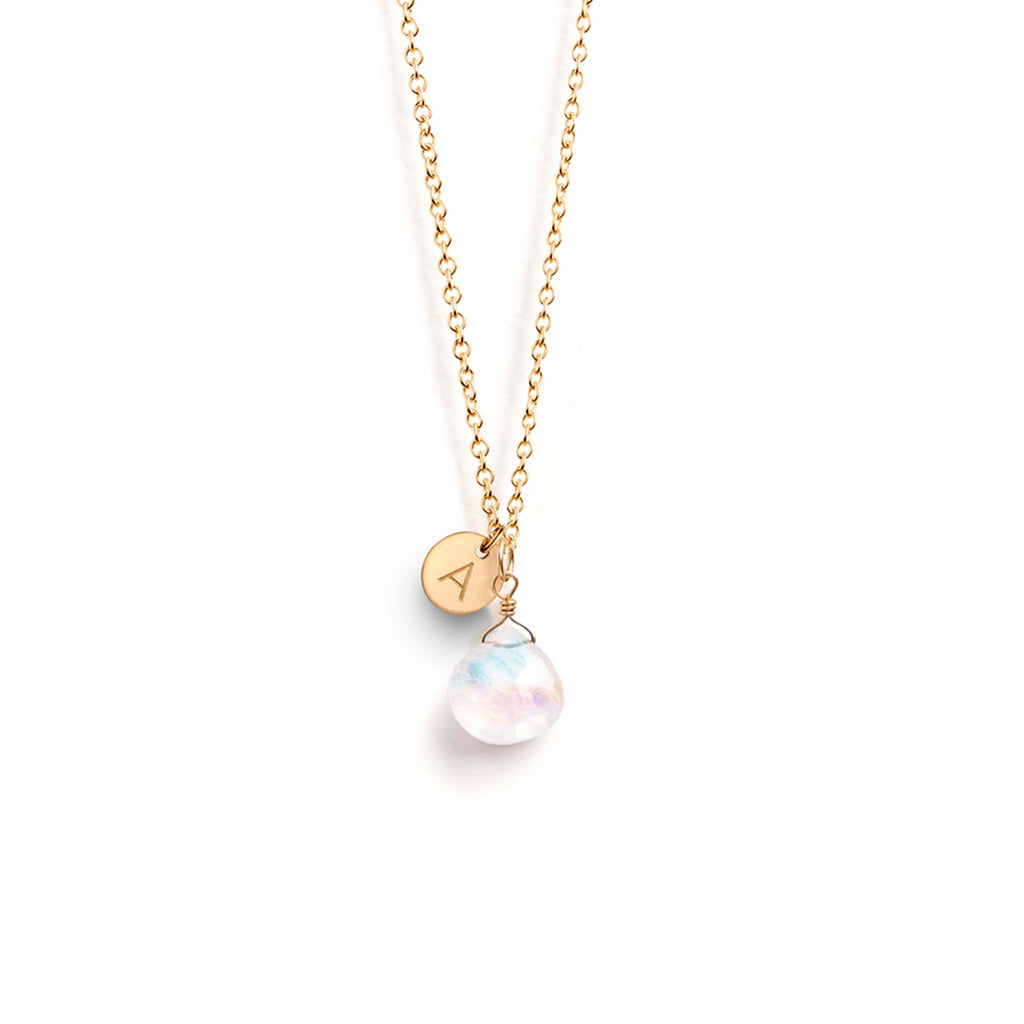 A June birthstone necklaces features a faceted rainbow moonstone gemstone, floating delicately on a fine gold chain. This birthstone necklace is personalised with a gold disc charm, hand-stamped with the letter A.