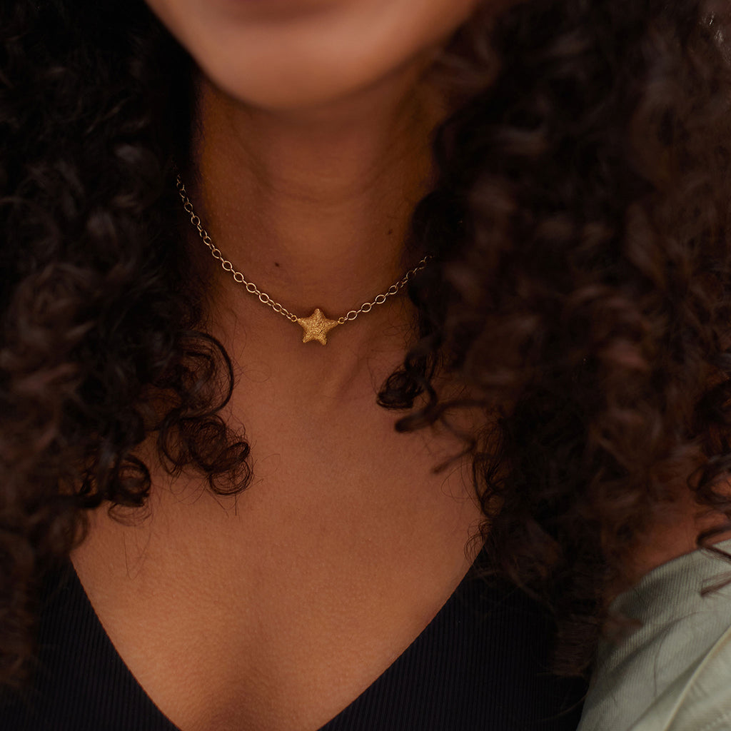 Wanderlust Life Star Wish Choker Necklace. A textured gold star fish sits symmetrically in the centre of a gold statement chain. Short in length, this piece is perfect for layering into your necklace stack, or wearing solo as a statement piece this summer. Shop the new Sea Dreams collection online at Wanderlust Life.