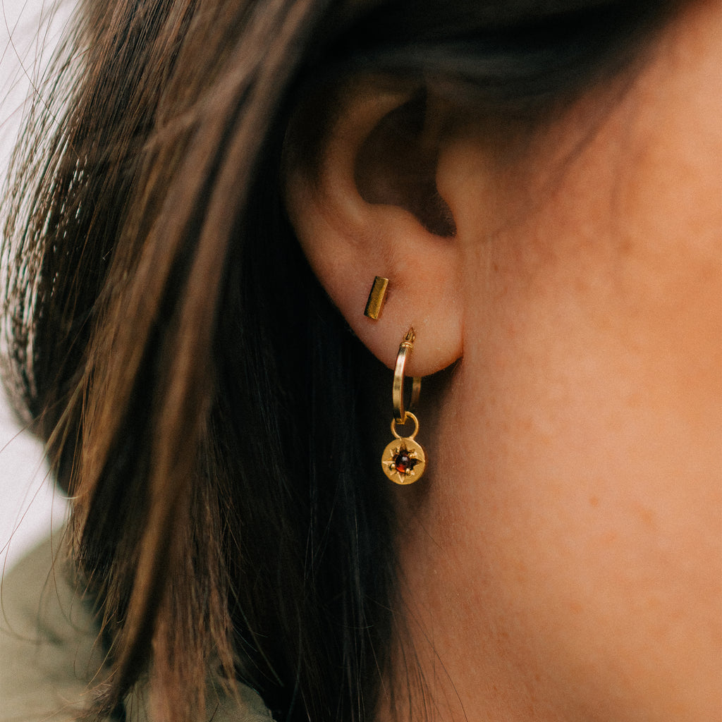 Tonina stud earrings. Gold bar studs make an impact styled into an ear stack. Worn with garnet amulet creole hoop earrings. 