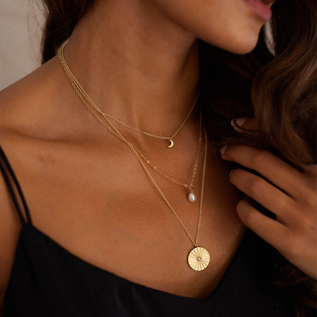 The Pearl Pendant Necklace is a freshwater pearl on a minimal, fine gold-fill chain. Layered with the Luna Crescent Moon Necklace and Pearl Sundial Necklace.