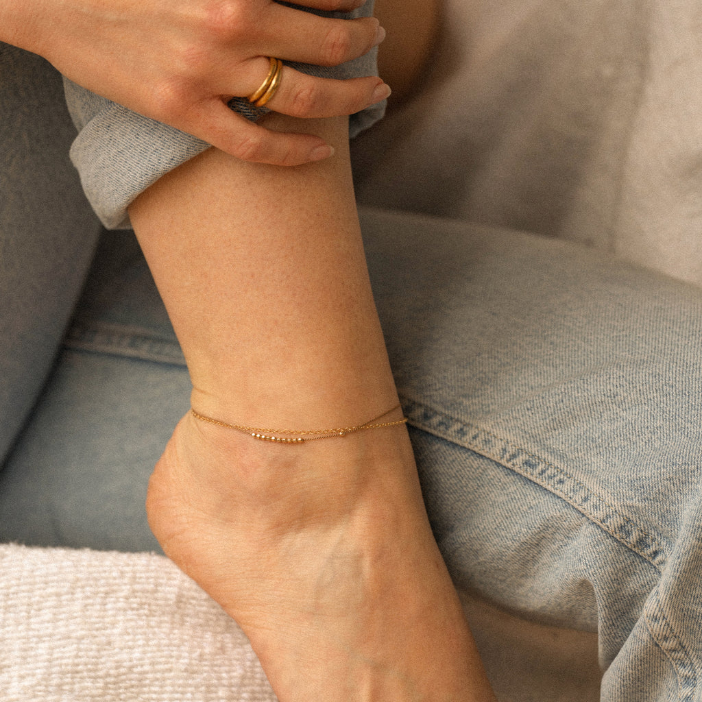 A delicate & beautiful mix of texture; gold, silk & tactile gold faceted beads. Finished with a hand stamped gemstone tag, and available with adjustable sizing. Handmade in our Devon studio. Shop anklets at Wanderlust Life.