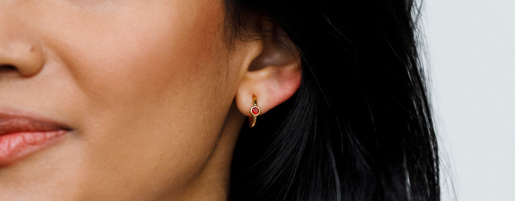 Birthstone Earrings. Stud hoop earrings feature a turquoise gemstone, styled alongside a minimal bar stud. Shop birthstone earrings, choose from 12 meaningful gemstones, perfect for gifts.