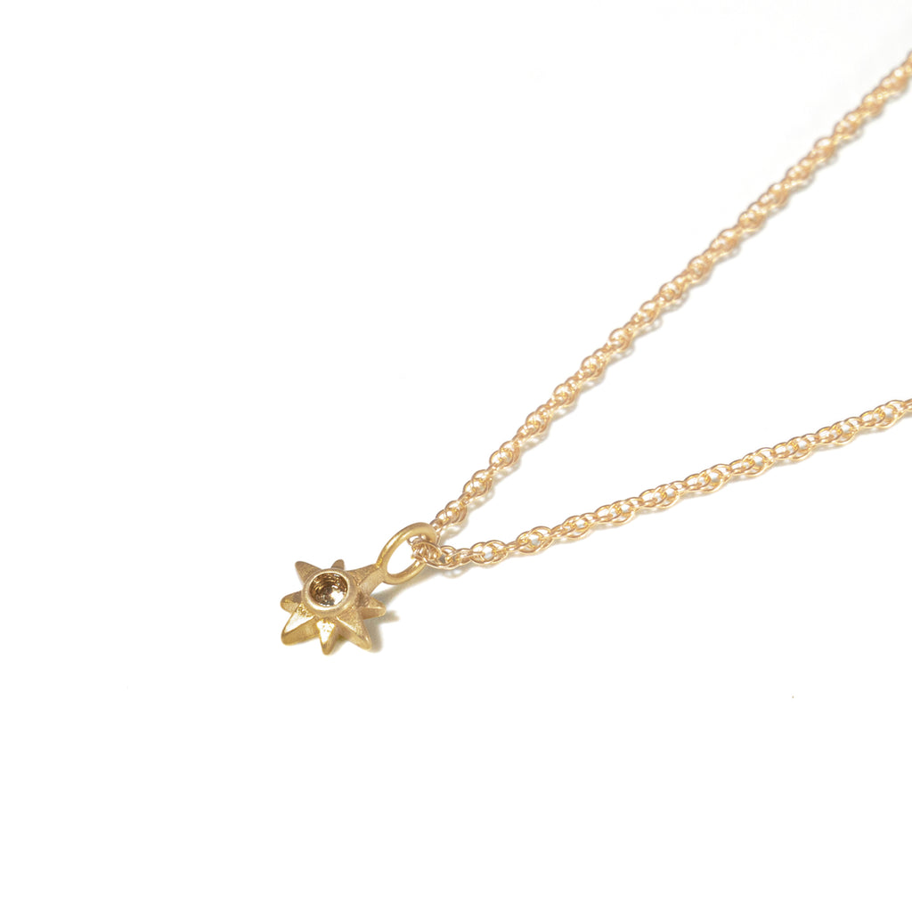 A choker style chain features white topaz set in a gold star, bringing flashes of light to dance at the neckline.