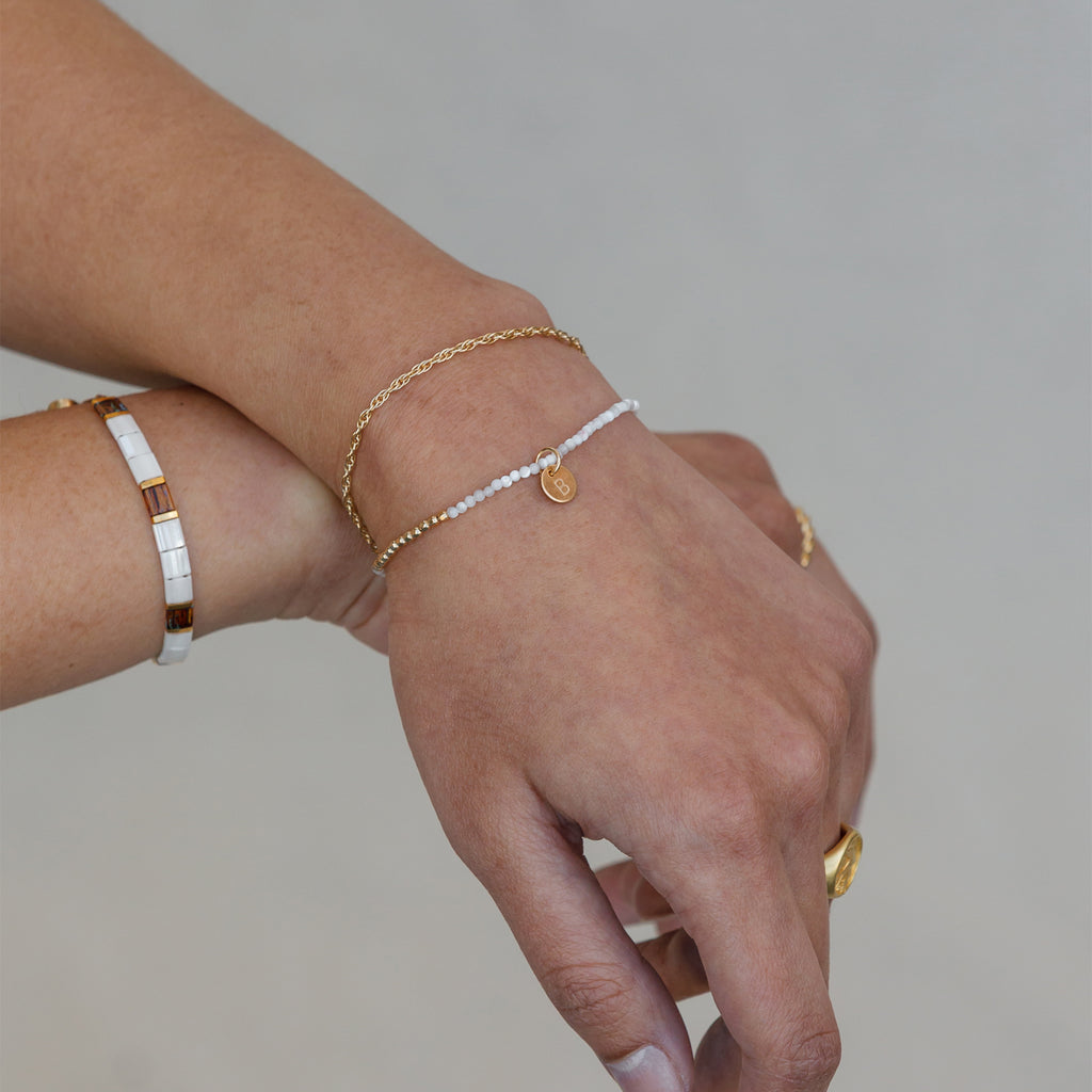 A reimagined version of our bestselling terrazzo bracelet, this pearly mosaic bracelet blends dreamy pearlescent glass tiled beads with tortoiseshell beads and gold accents. Styled with the oceanus mother of pearl beaded bracelet and coraline chain.