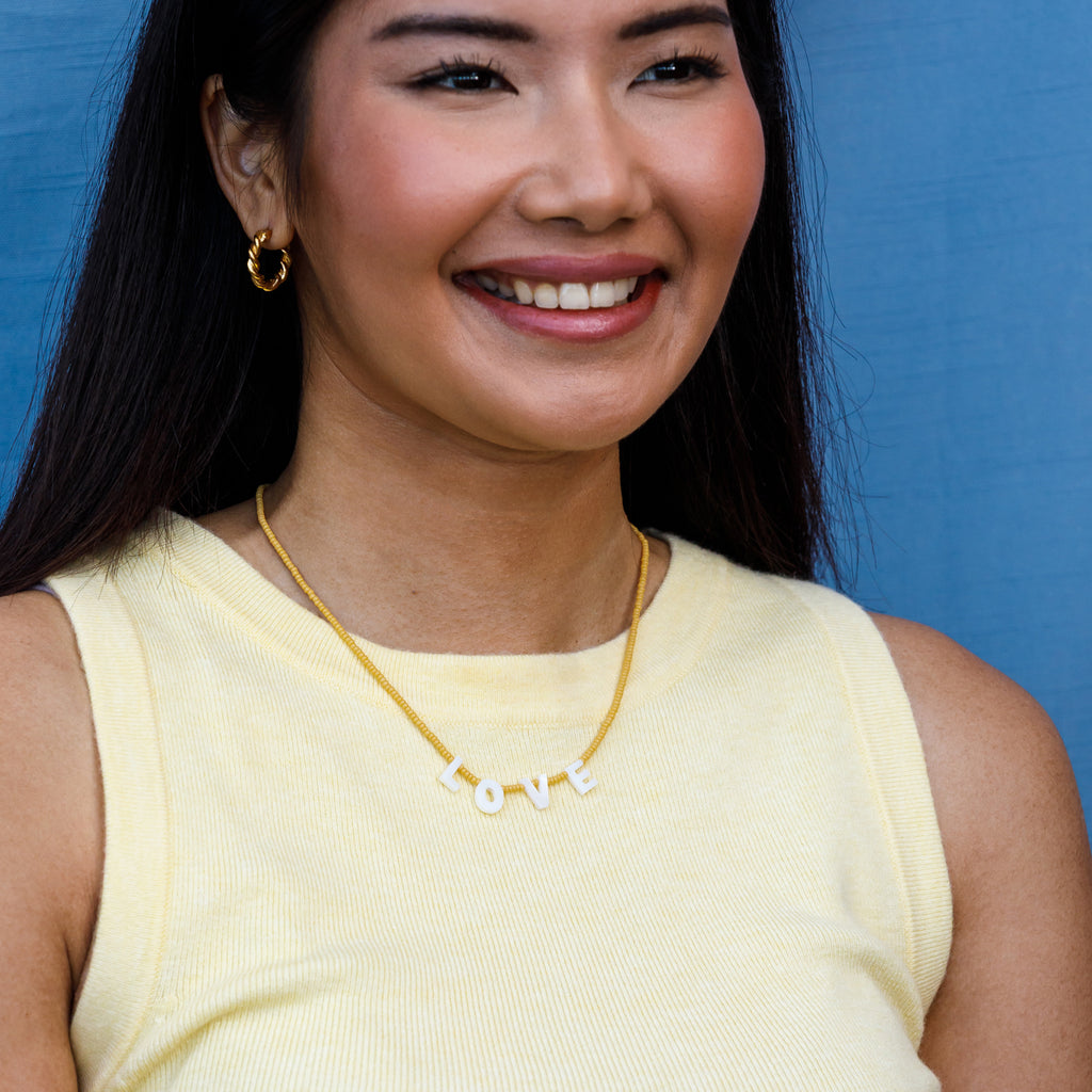 Featuring seed beads in sun-soaked lemon, our beaded necklace showcases mother-of-pearl letters that spell out L-O-V-E. 