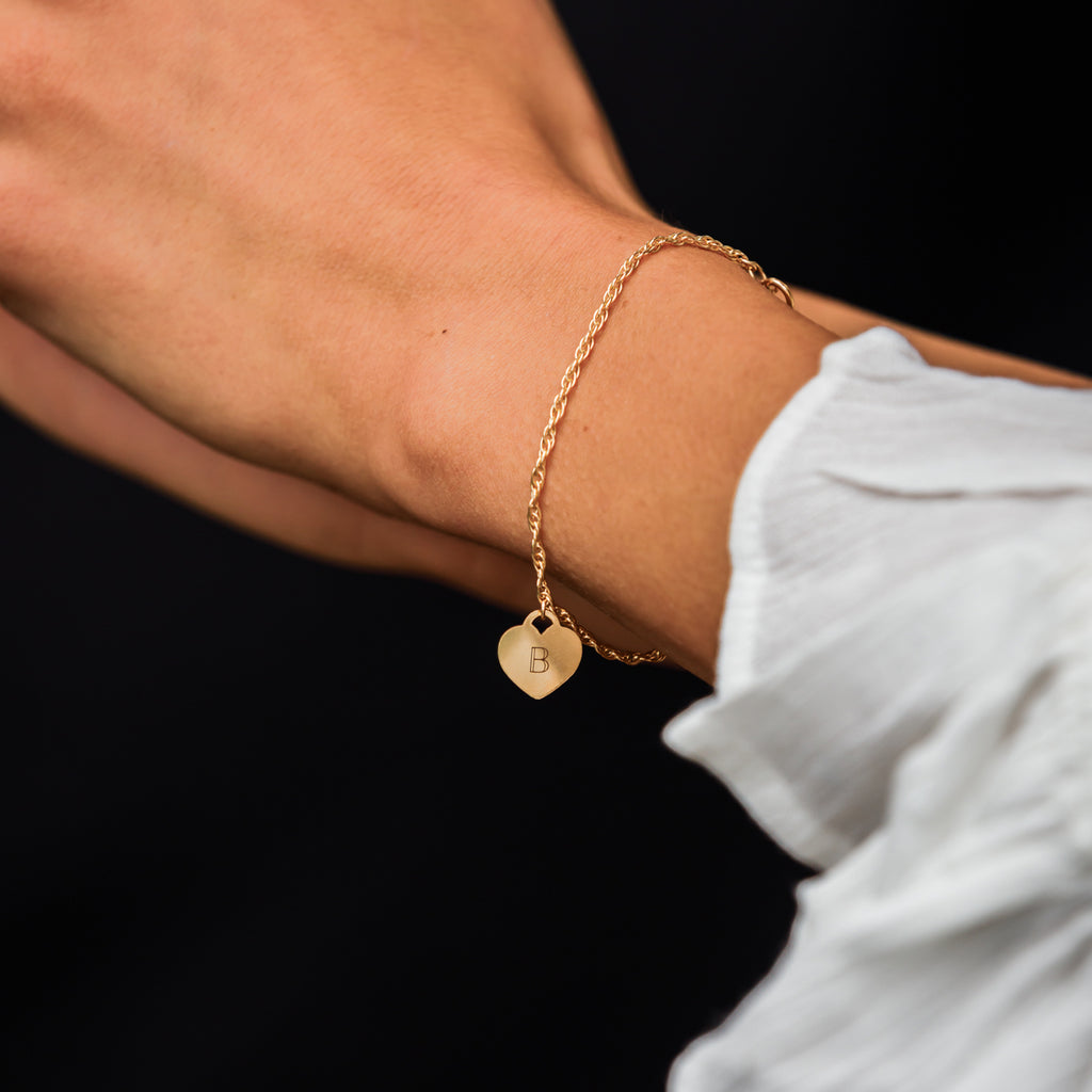 Charged with meaning, an engravable heart slides on an adjustable gold chain bracelet.