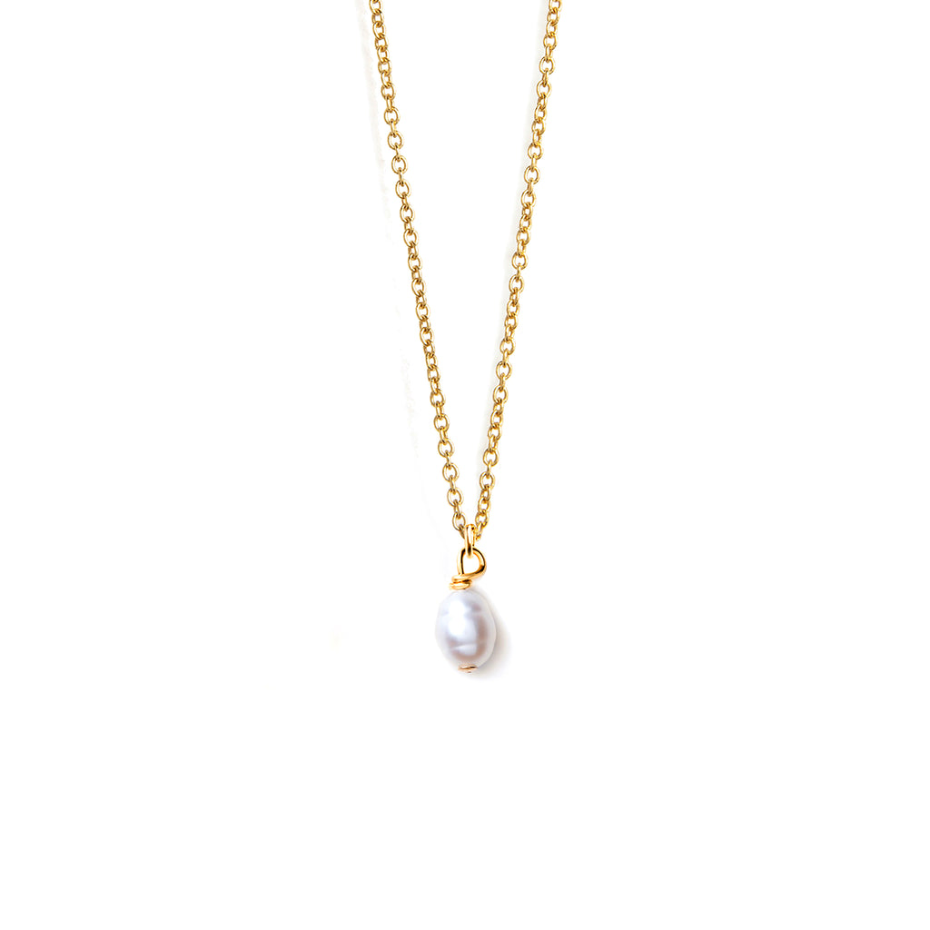 A freshwater pearl is suspended from a fine gold chain. A modern and minimal iteration of a timeless classic, this pearl necklace is a versatile piece and can be worn solo or layered into your necklace stack.