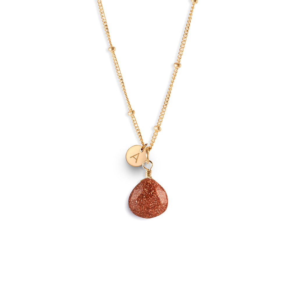 A radiant man-made glass goldstone with copper sparkles reminiscent of a miniature glitterball hangs from a minimal gold-fill satellite chain. Personalised with a hand stamped 14k gold fill initial tag. Designed and handcrafted in Devon. 