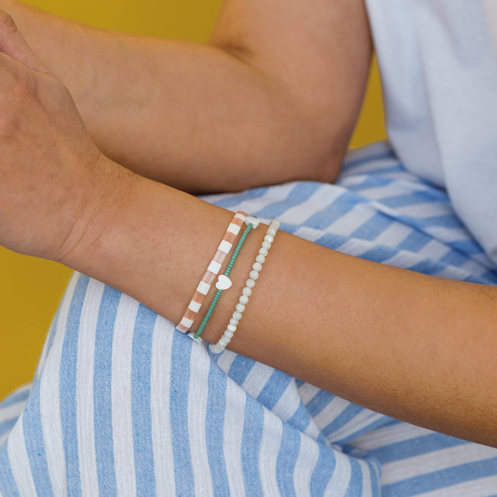 Shell pink layering bracelet layered with ocean blue heart beaded bracelet and kai mother of pearl beaded bracelet.
