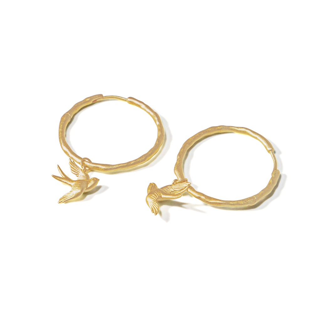 A 3-dimensional swallow charm suspends from a textured and lightly hammered hoop with a hidden hinge closure.&nbsp;