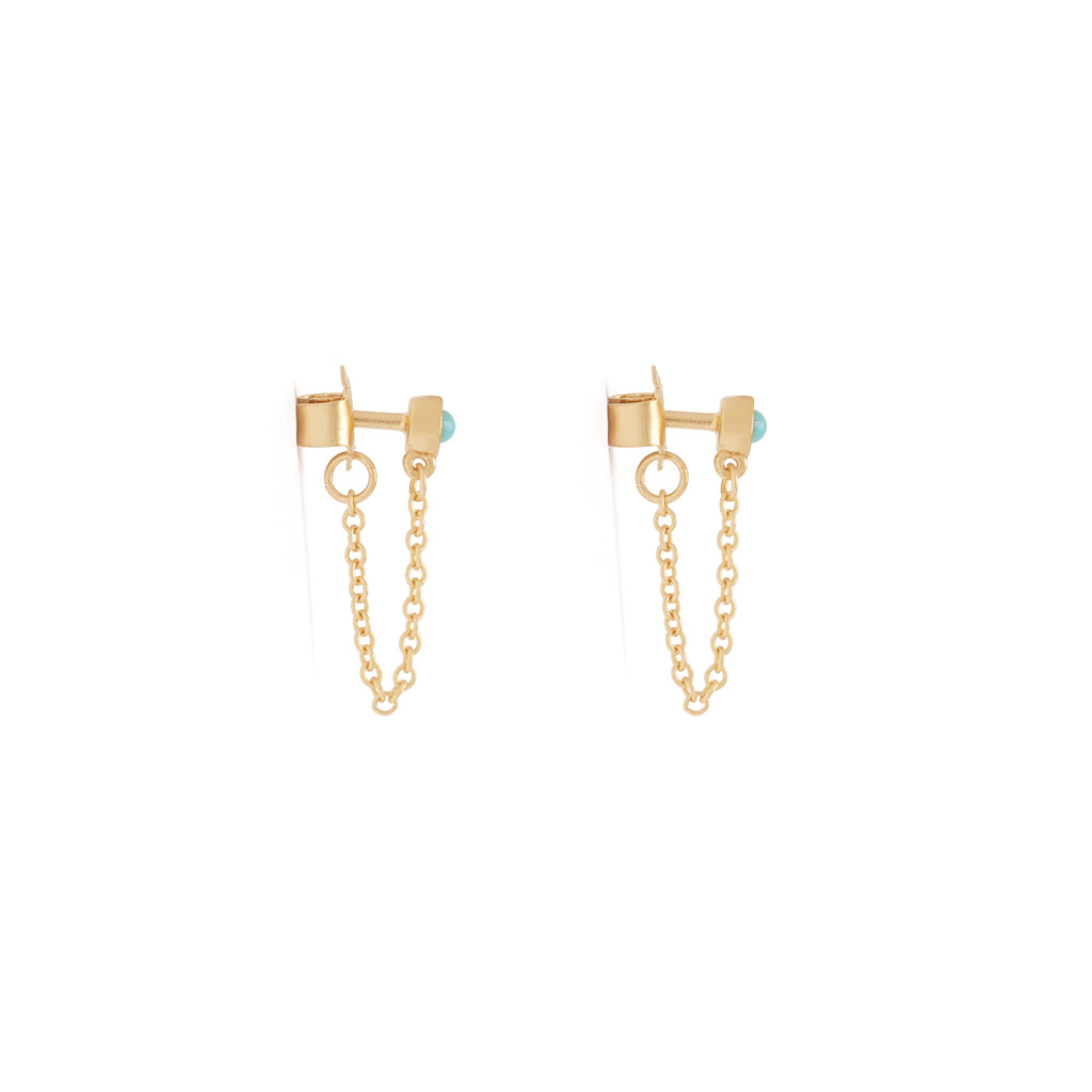 A turquoise stud earring connects to its backing with a dainty gold chain that adds movement and energy to your ear stack.