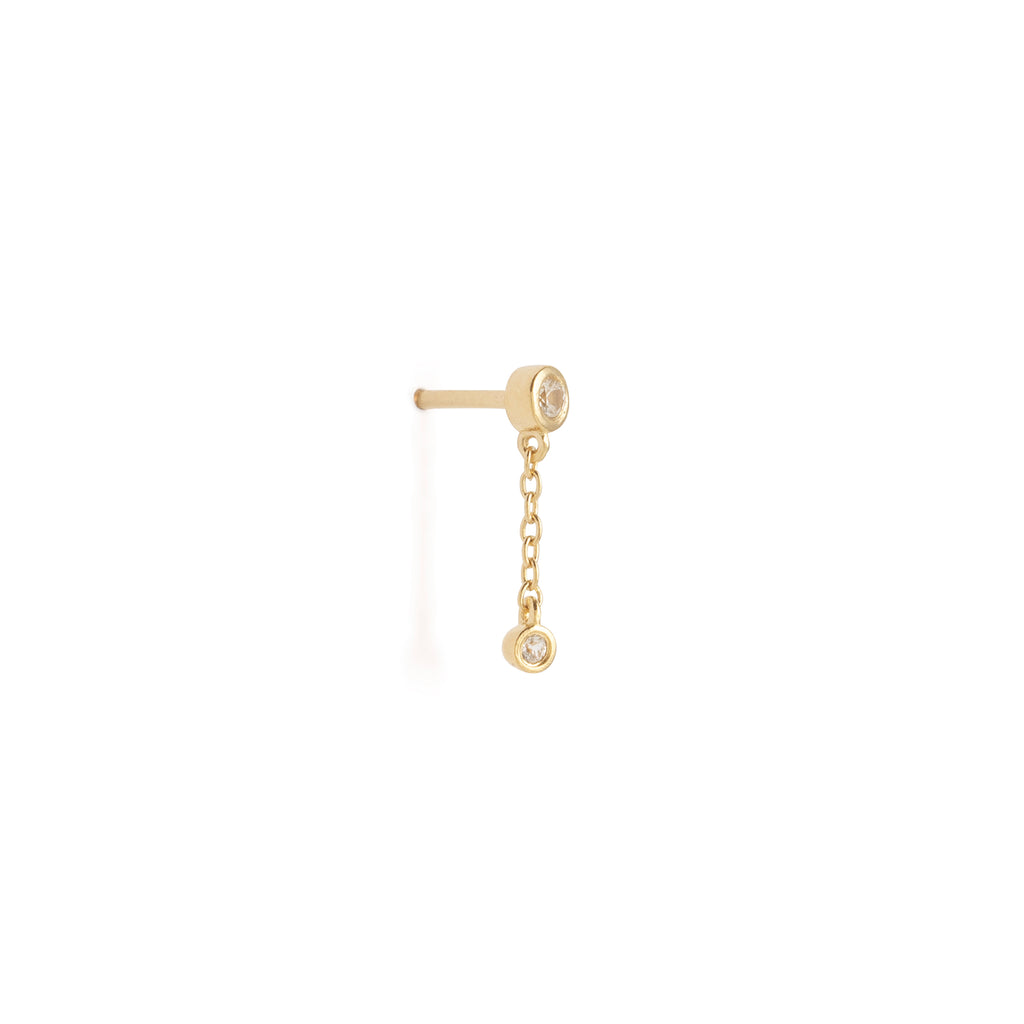 Gold earring with a chain and small gemstone on a white background