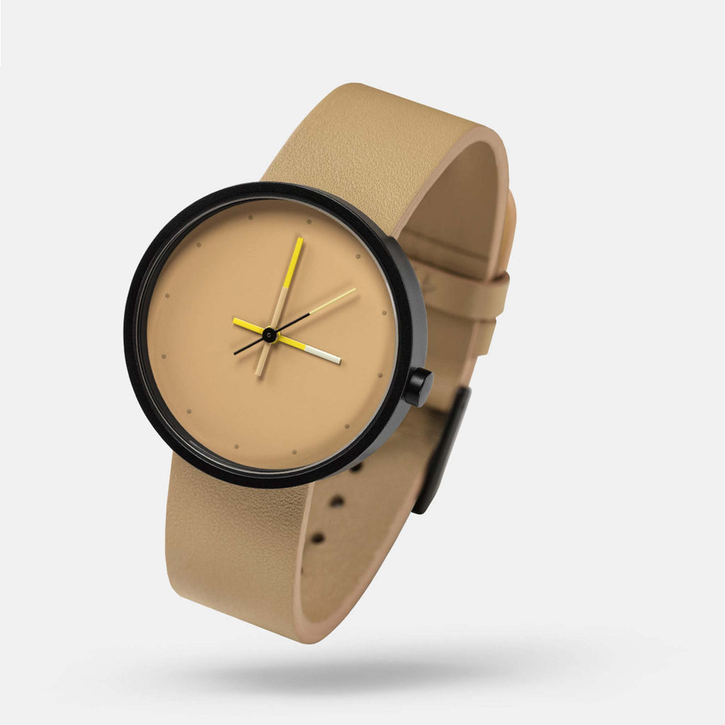 A watch featuring a black stainless steel case, a neutral beige face and strap, with watch hands in vivid yellow to accent the muted tones.