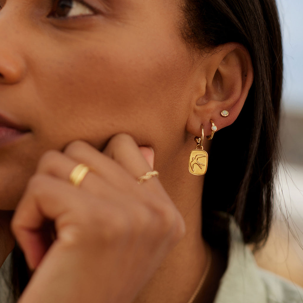 Wanderlust Life Aeris Drop Hoop Earrings. New in the Elemental Collection, gold hoop earrings with charms. A hand-cast swallow adorns the charms. Proudly designed in our Devon studio and handcrafted in the UK by our Wanderlust Life global artisan partners.