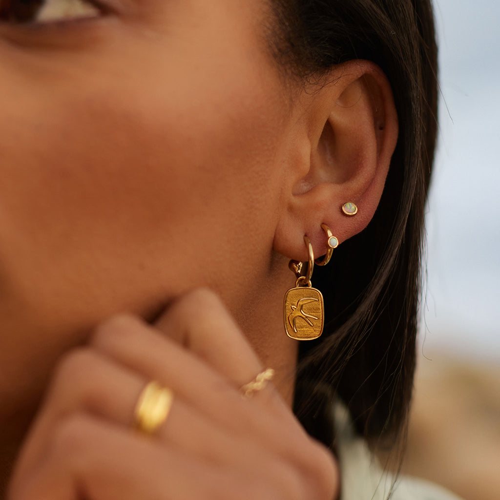 Wanderlust Life Aeris Drop Hoop Earrings. New in the Elemental Collection, gold hoop earrings with charms. A hand-cast swallow adorns the charms. Proudly designed in our Devon studio and handcrafted in the UK by our Wanderlust Life global artisan partners.