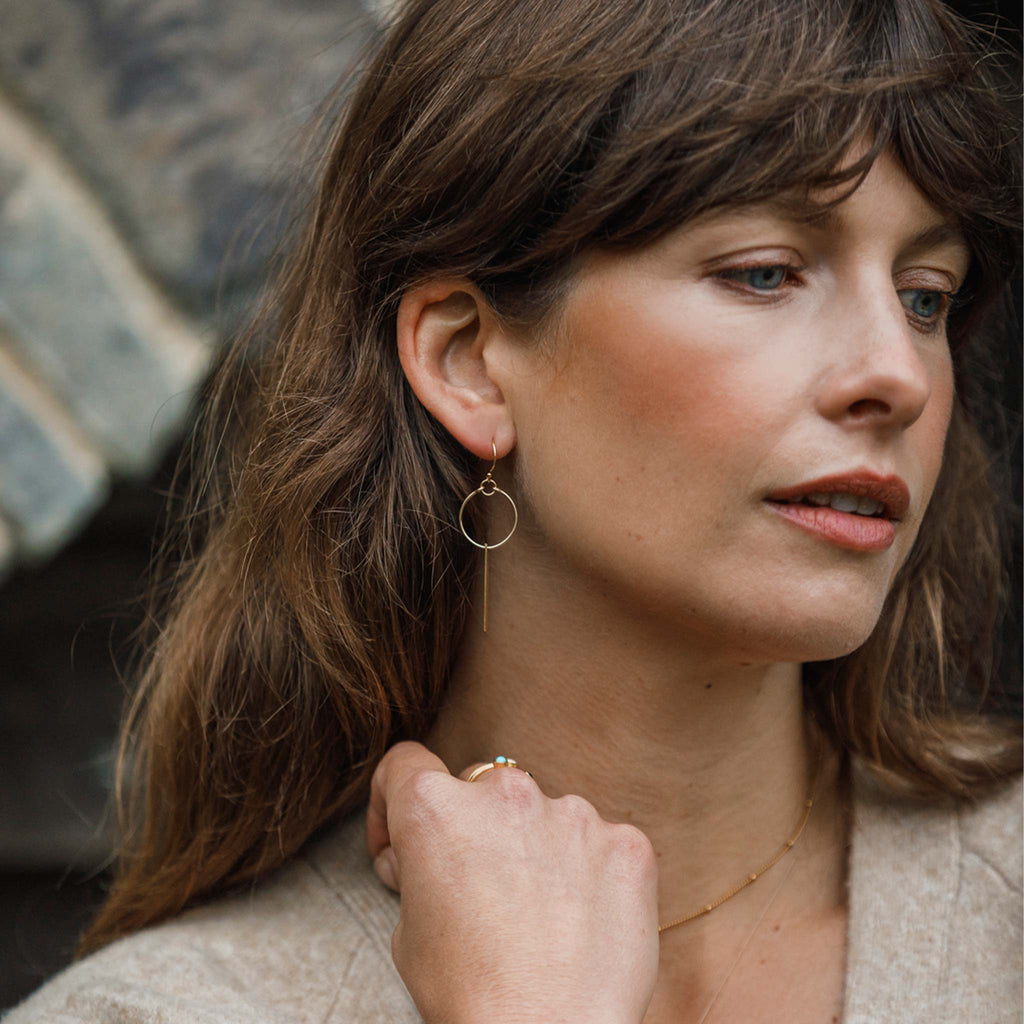 Wanderlust Life Ethically Handmade jewellery made in the UK. Minimalist gold and fine cord jewellery. Aktis sculptural hoop earring with hoop and drop gold bar.