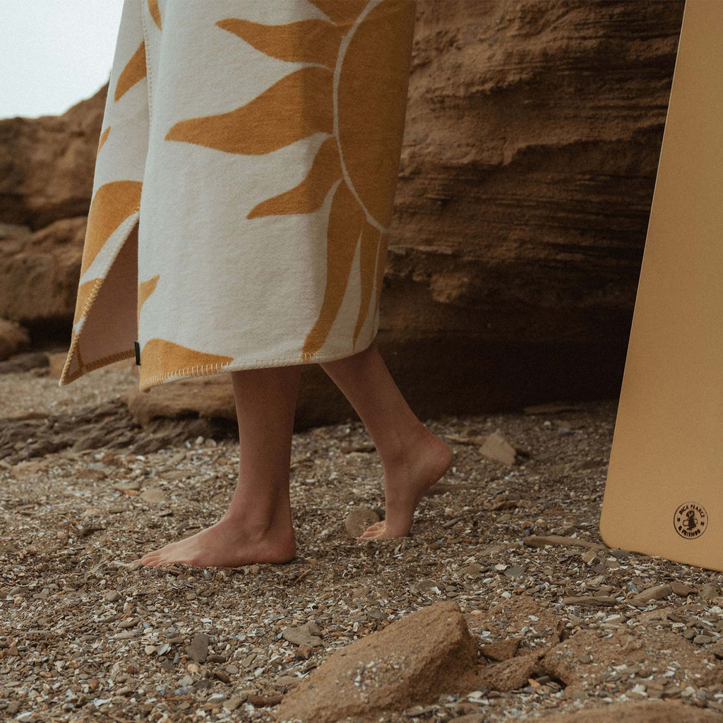 Created with recycled cotton, a reversible blanket featuring a sun motif with golden yellow tones. Designed by Wanderlust Life and Atlantic Blankets, made in the UK.