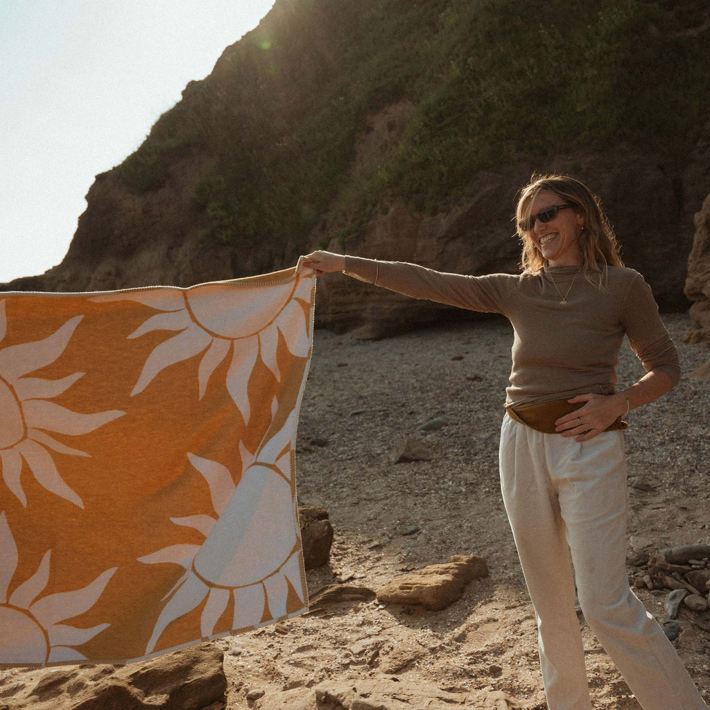 Created with recycled cotton, a reversible blanket featuring a sun motif with golden yellow tones. Designed by Wanderlust Life and Atlantic Blankets, made in the UK.