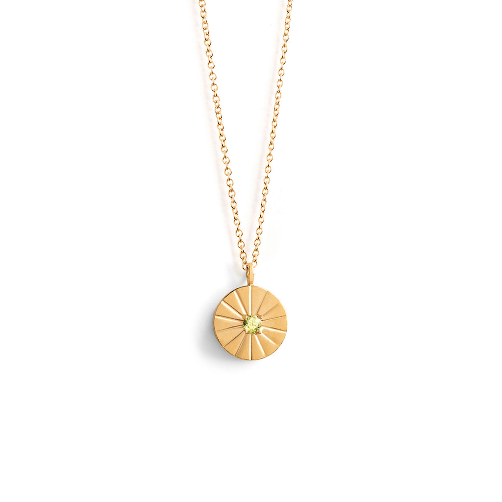 An August Birthstone necklace features a solitary peridot gemstone in the centre of a circular pendant. Etched beams inspired by sundials meet in the middle surrounding a green peridot gemstone. The back of the pendant can be personalised with your own engraving using our free engraving service.