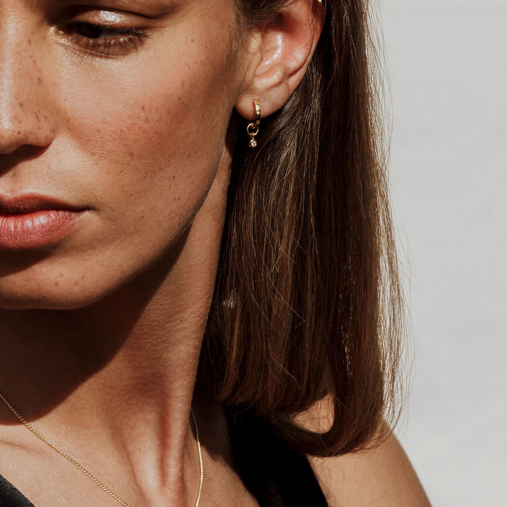 Minimal and modern, the Axios Diamond Huggie Hoop Earrings in a shiny finish on recycled 9k gold. Designed in Devon.
