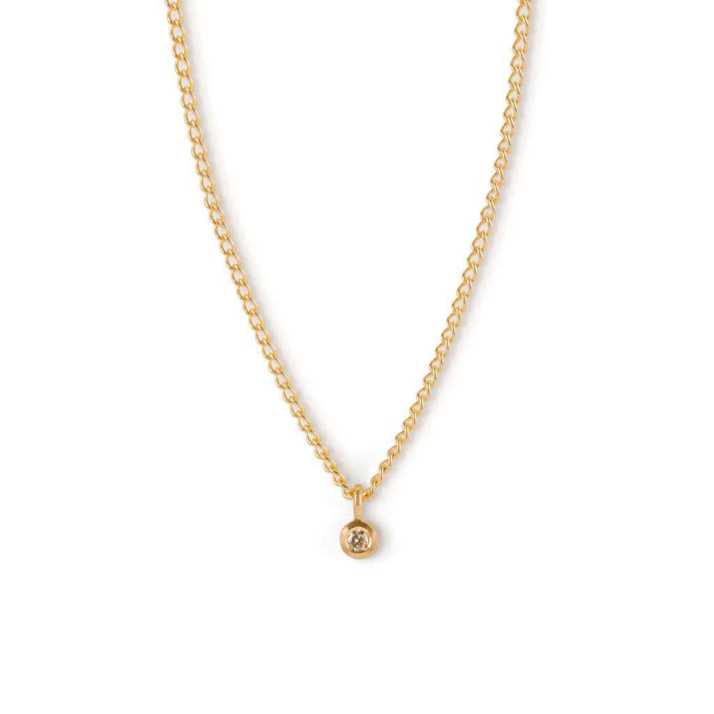 The Axios Diamond Necklace features a bezel set diamond  on a solid 9k yellow gold chain. The chain is a classic curb style of flat links. This necklace blends our signature minimalism with sustainability, using recycled gold and lab-grown diamonds.
