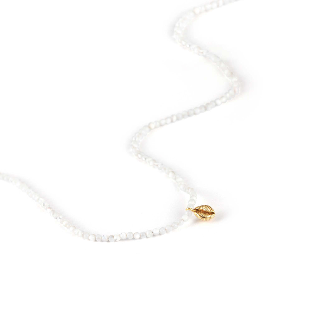 A dainty hand-cast cowry shell dances on a mother of pearl beaded choker necklace.