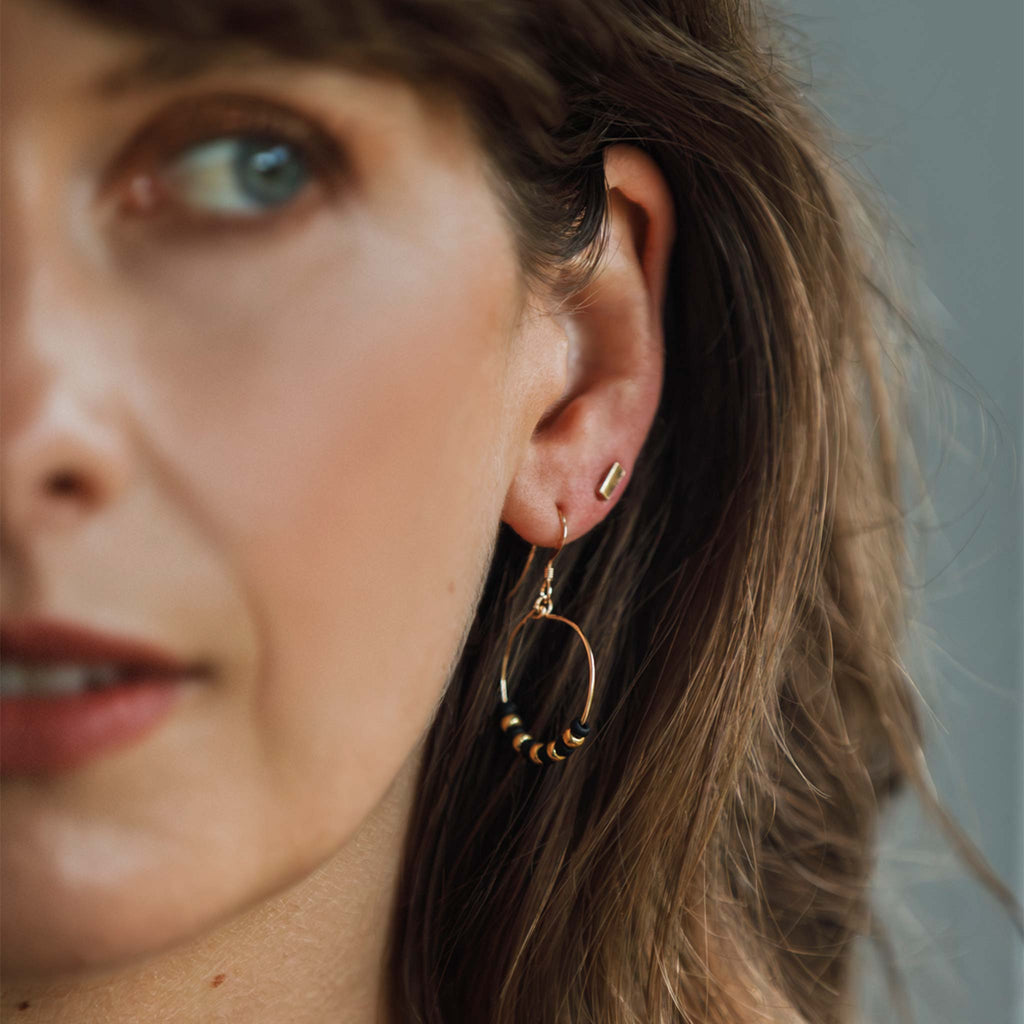 The Copacabana Noir Earrings are beaded black and gold earrings, styled beside the Tonina bar studs in versatile ear stack.
