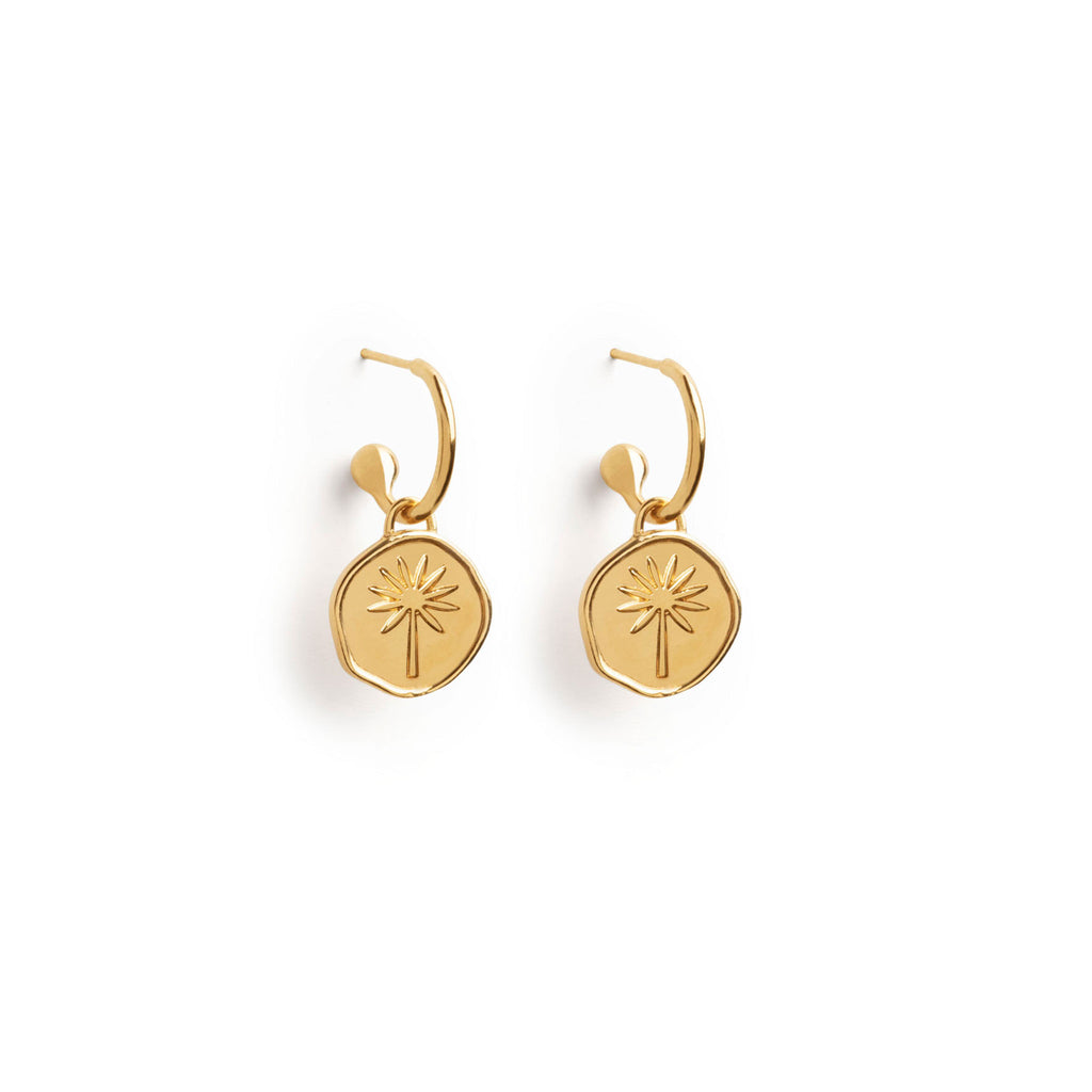 Wanderlust Life Terra Drop Hoop Earrings. New in the Elemental Collection, a hand-cast disc featuring a palm tree hangs on a gold hoop earring. The perfect summer staple to add to your ear stack. Made with recycled materials. Proudly designed in our Devon studio, and handcrafted by our Wanderlust Life global artisan partners. 
