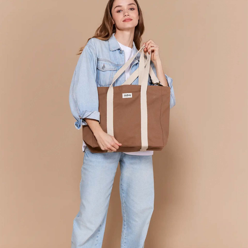 Crafted with organic cotton, a brown tote bag ideal for everyday that can be worn as a crossbody with an adjustable cream strap or as a shoulder bag.