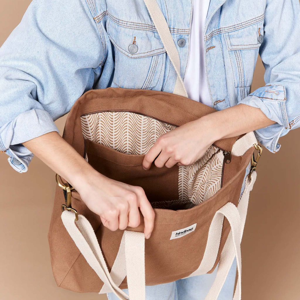 Crafted with organic cotton, a brown tote bag ideal for everyday that can be worn as a crossbody with an adjustable cream strap or as a shoulder bag.