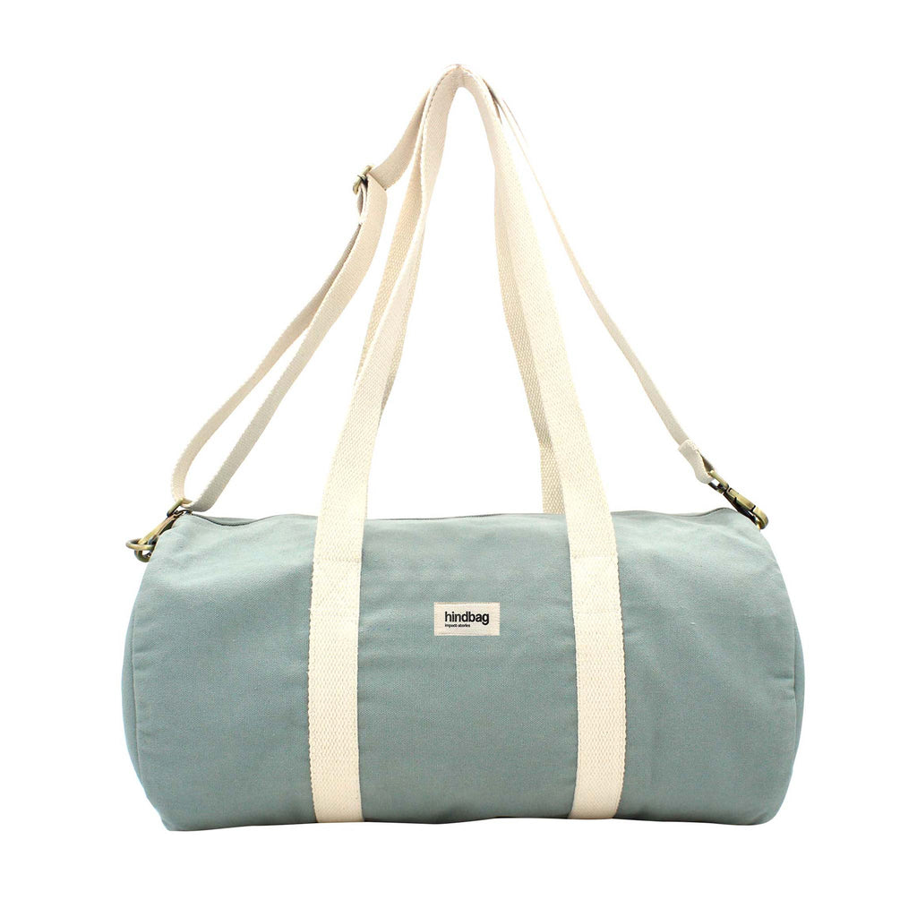 A rounded duffel bag in a shade of blue sage. Theres a detachable strap and two other straps in cream. 