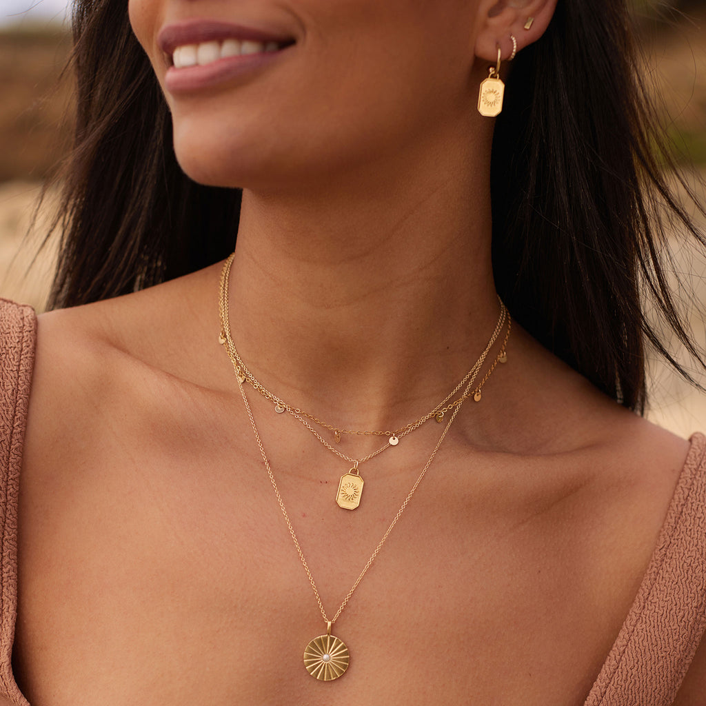 Wanderlust Life Pearl Sundial Necklace. Etched beams radiate from a pearl gemstone on a long chain. This pearl necklace is a modern statement piece for layering. Designed in our Devon studio, and handcrafted by our Wanderlust Life Global Artisan Partners. Shop minimal gold jewellery online.