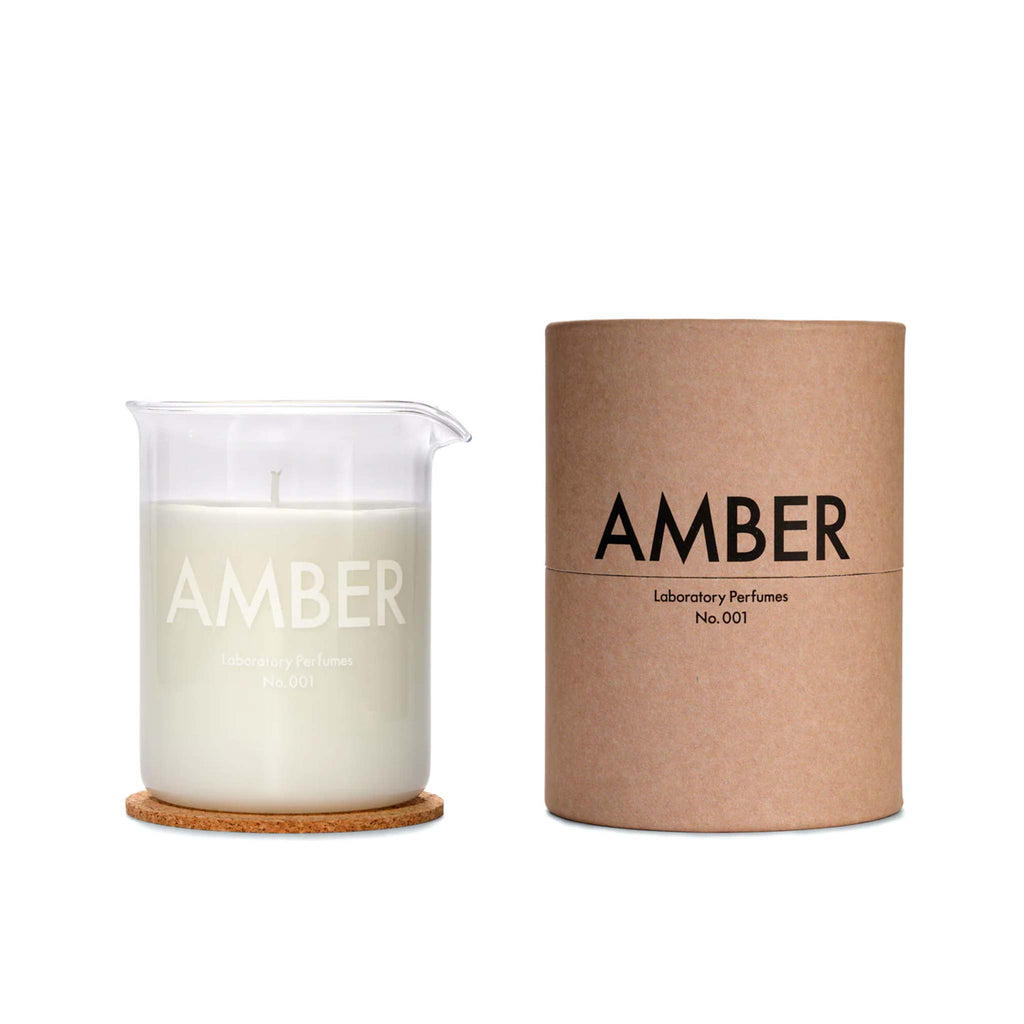 Laboratory's Amber Candle comes in a glass in a style of a beaker, with a cork mat to place underneath. Packaged in a cardboard cylinder. 