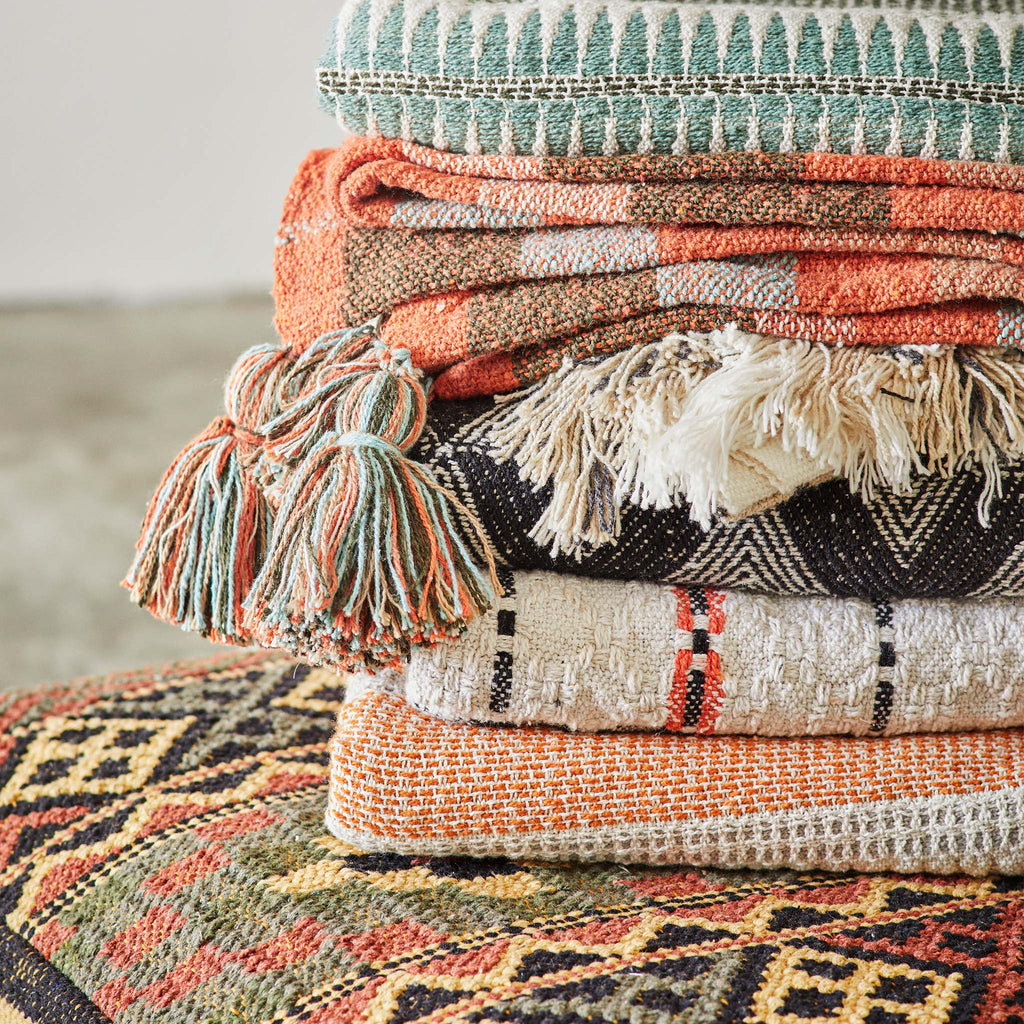 Colourful cotton throw blankets by Madam Stoltz are stacked, each in a unique woven pattern.