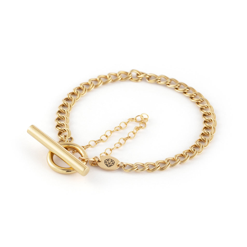 A flat double curb chain is set off with a ring and bar toggle closure to sit upon the wristbone. The bracelet features a safety chain to keep it safely secure whilst wearing.