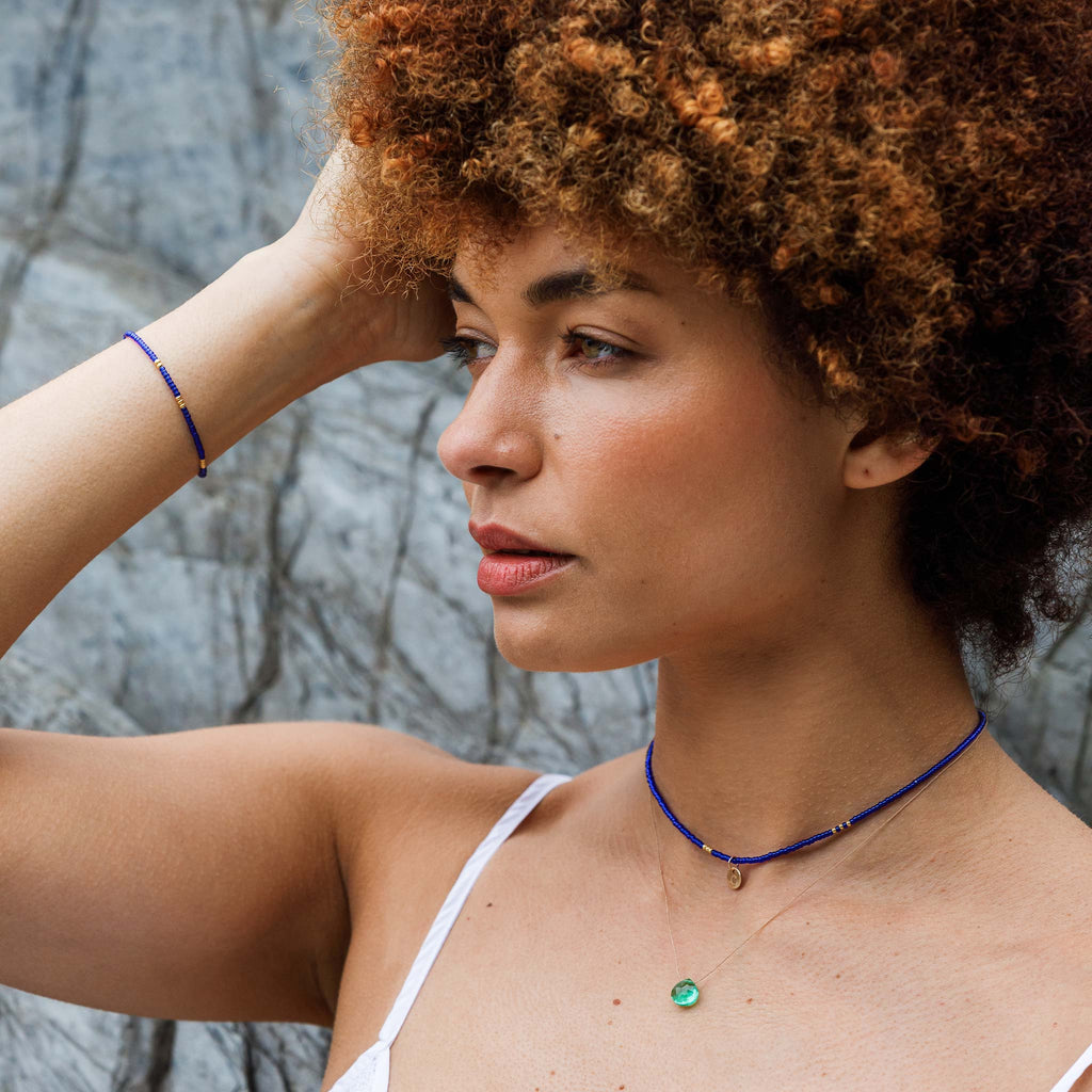 Featuring glass seed beads in bright royal blue and gold, our choker-style necklace provides a pop of texture. Styled with a matching cobalt blue beaded bracelet and minimal fine cord necklace in seafoam green quartz.