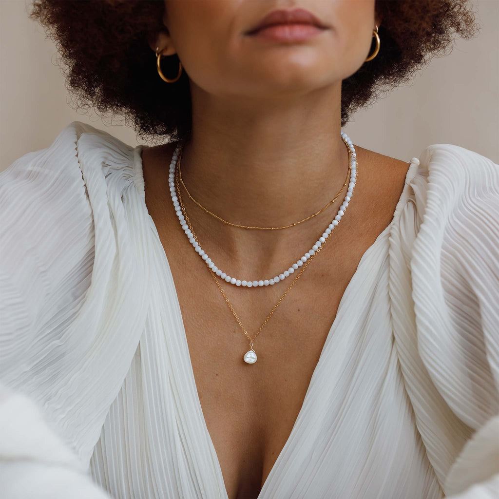 The Mother of Pearl Gemstone Necklace is a pearly white and iridescent gemstone. Worn with a beaded mother of pearl gemstone necklace and a layering chain.