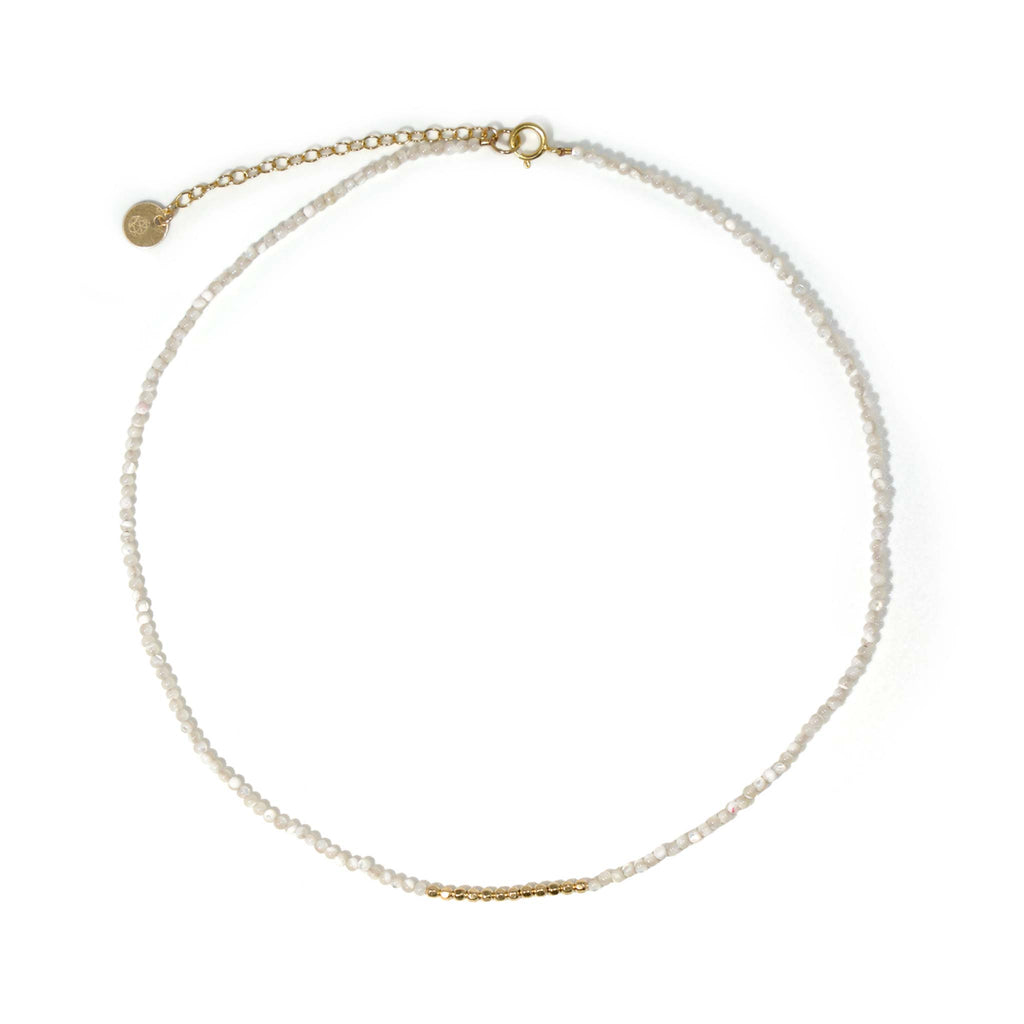 A dainty choker-length beaded necklace with lustrous mother of pearl and an accent of gold beads that shimmer like ocean waves under the sun.