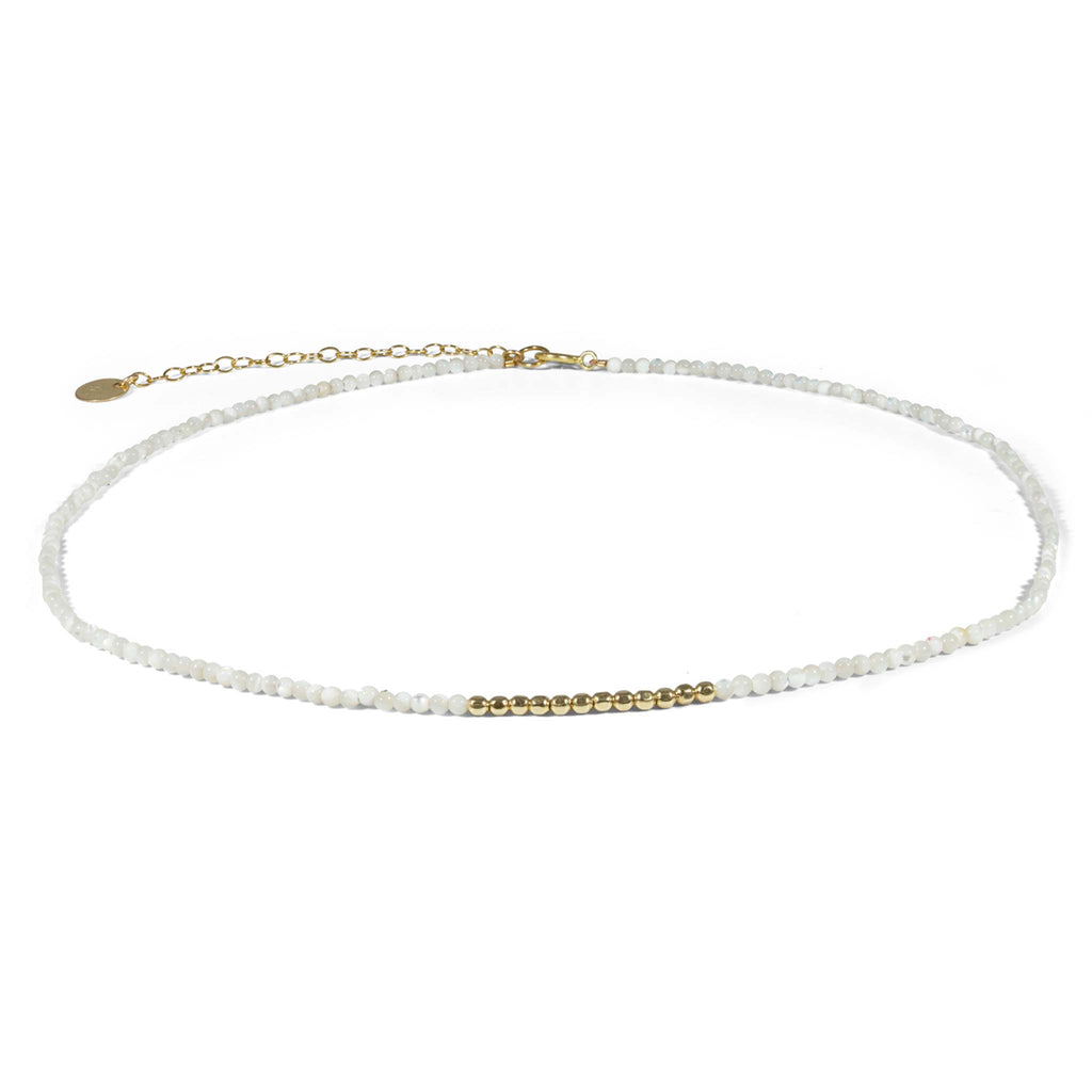 A dainty choker-length beaded necklace with lustrous mother of pearl and an accent of gold beads that shimmer like ocean waves under the sun.