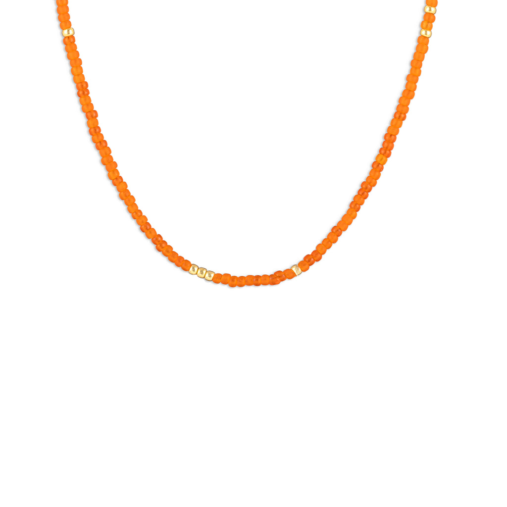 The Tangiers Beaded Necklace features orange seed beads, contrasted with flecks of gold beads in an irregular pattern. 