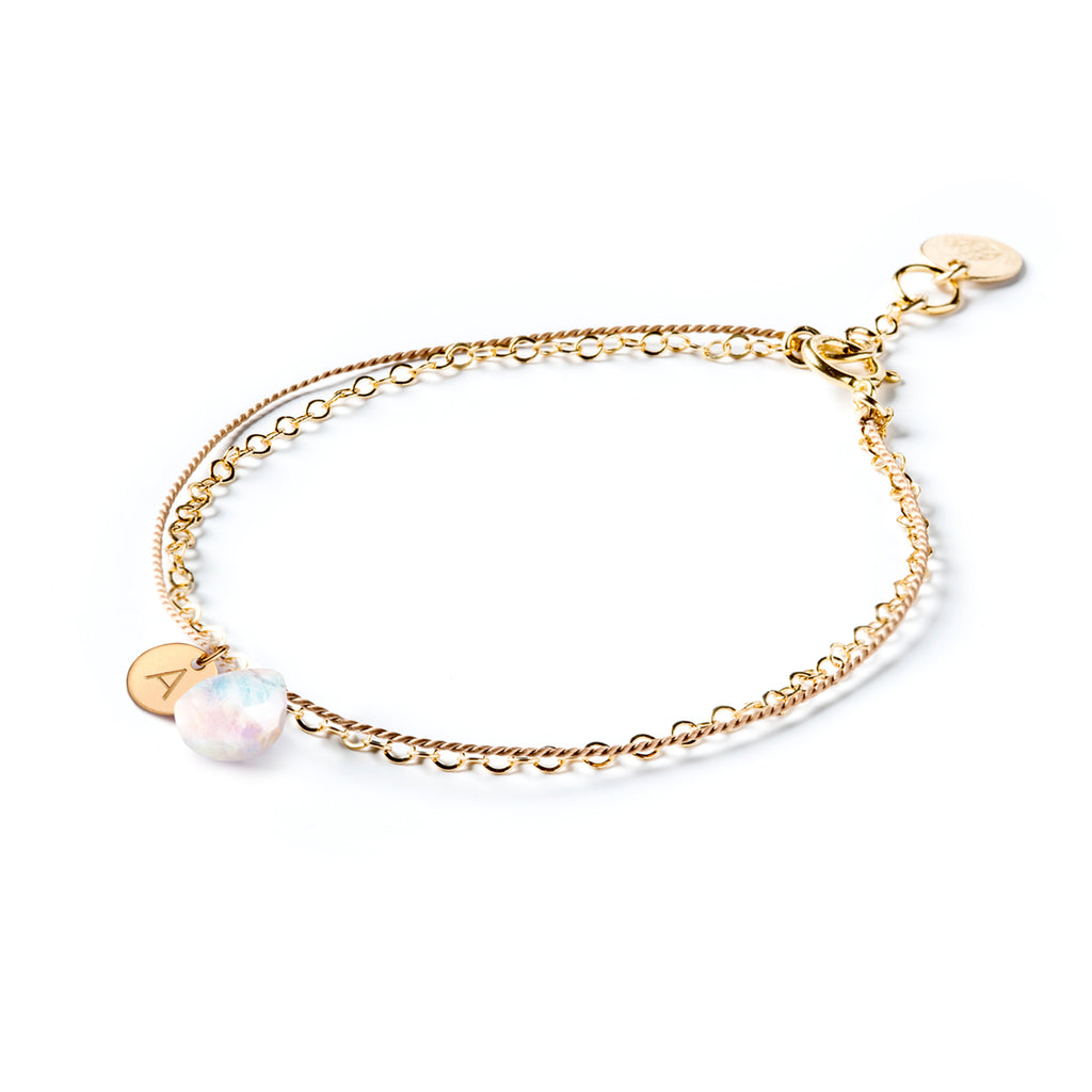 June Birthstone Bracelet personalised with an initial tag. Choose your initial and our jewellery maker’s personalise your birthstone bracelet. The bracelet creates the appearance of two individual bracelets layered into a stack, but the bracelet combines a layer of silk with a fine gold chain, decorated with a rainbow moonstone in Wanderlust Life Jewellery’s signature faceted style. 